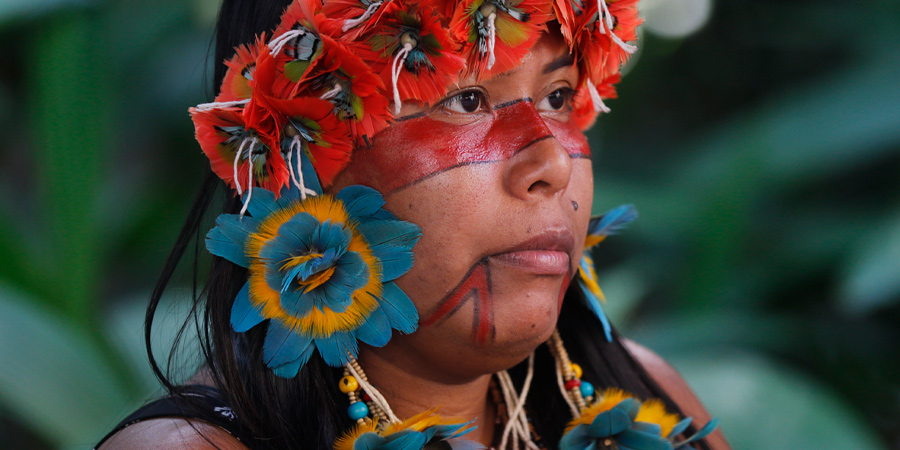 Mulher indígena com pintura no rosto e um cocar na cabeça