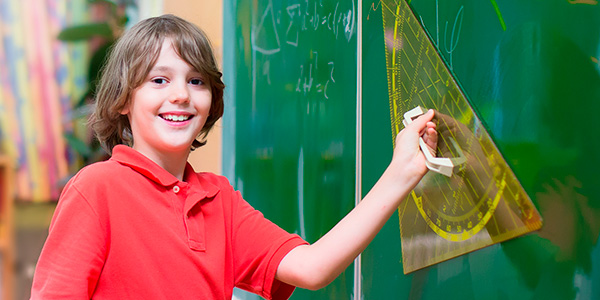 Aluno mostra régua no quadro do Colégio João Paulo I transformando a matemática em uma experiência divertida.