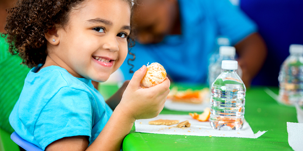 Menina come fruta e toma água numa alimentação saudável orientada pelo Colégio João Paulo I. 